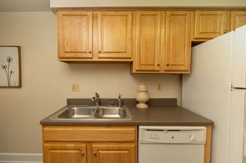 A kitchen with wooden cabinets and a white refrigerator.at Chapel Valley Townhomes, Nottingham, MD 21236